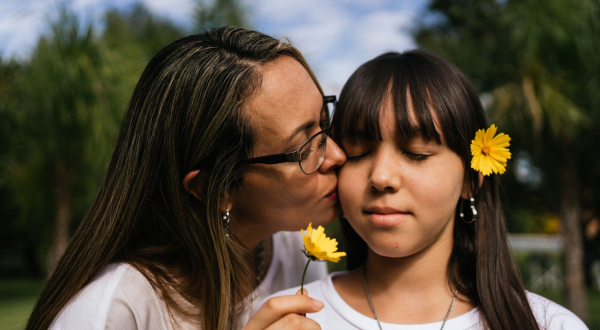 Mother kissing child with flower
